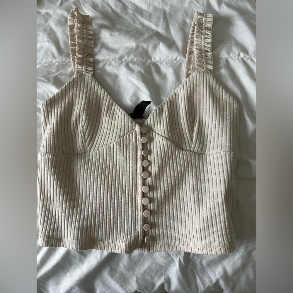 tan/cream colored tank top with buttons going down the tank